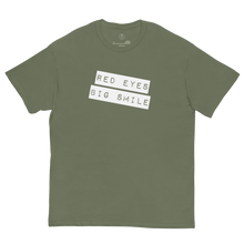 Load image into Gallery viewer, Covert Grin Tee in army green laid flat, showcasing the subtle &#39;Big Smile Red Eyes&#39; design for the discerning fashion operative