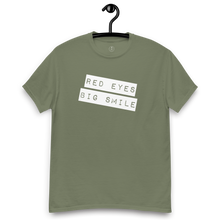 Load image into Gallery viewer, Army green Covert Grin Tee hanging, ready for action with its discreet yet expressive &#39;Big Smile Red Eyes&#39; motif.