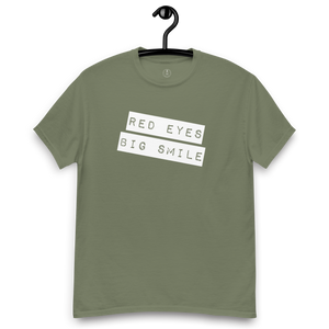 Army green Covert Grin Tee hanging, ready for action with its discreet yet expressive 'Big Smile Red Eyes' motif.