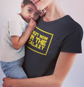 A joyful mother, wearing the Galactic Queen Tee, embraces her child, showcasing the strength and love of a Star Wars mom.